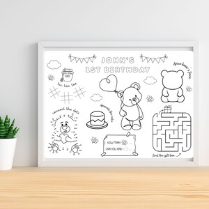Op de afbeelding: Een zwart-wit activiteitenvellen in een witte lijst, voor een eerste verjaardag. Het bevat een doolhof, verbind-de-stippen, boter-kaas-en-eieren en andere spelletjes. De tekst luidt "JOHN'S 1ST BIRTHDAY" en "draw bear's face".