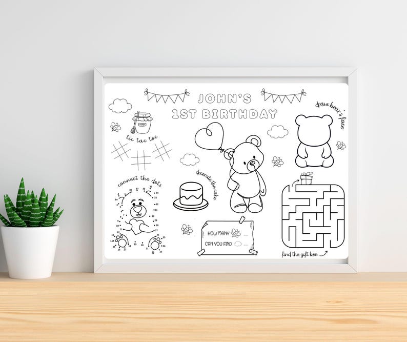Op de afbeelding: Een zwart-wit activiteitenvellen in een witte lijst, voor een eerste verjaardag. Het bevat een doolhof, verbind-de-stippen, boter-kaas-en-eieren en andere spelletjes. De tekst luidt "JOHN'S 1ST BIRTHDAY" en "draw bear's face".
