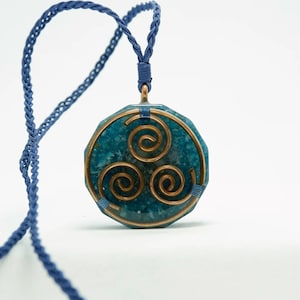 May include: A blue and copper pendant necklace featuring a triple spiral design. The pendant is crafted from a blue stone with copper wire wrapped around it. The necklace is made of a blue cord.