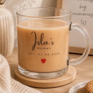 Personalised mummy glass mug filled with tea, featuring custom name and established date, displayed in a warm neutral home décor setting.