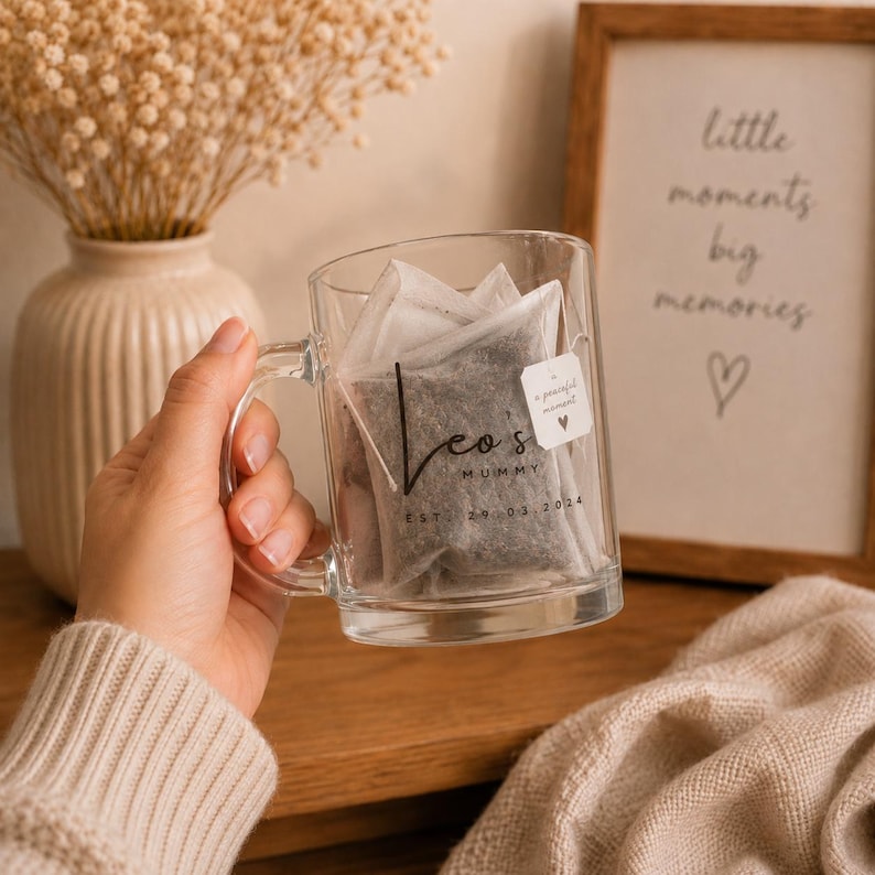 Personalised mummy glass mug with custom name and established date, presented with teabags in a cosy neutral home setting, perfect as a thoughtful new mum gift.