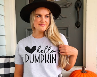 Pode incluir: Uma camiseta cinza com um coração preto e o texto "hello pumpkin" em fonte manuscrita.