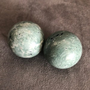 Peut inclure: Deux sphères de marbre vert et blanc avec des taches noires. Les sphères sont lisses et polies.