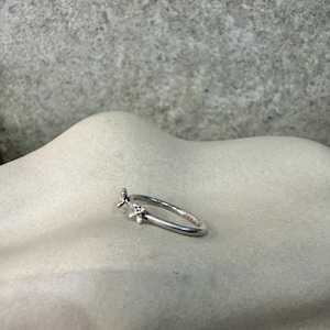 Puede incluir: Un anillo de plata con dos pequeños diseños de flores en la banda.