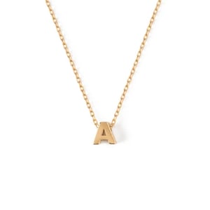 May include: Gold-coloured necklace featuring the letter "A" pendant. The pendant is a block letter style, suspended from a delicate chain. The necklace is set against a white backdrop.