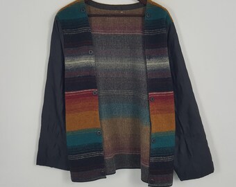 May include: A multi-colored, button-down jacket with a striped pattern in shades of teal, orange, red, and gray. The jacket has black sleeves and is displayed on a wooden hanger against a white background. The jacket is a unique piece of apparel.