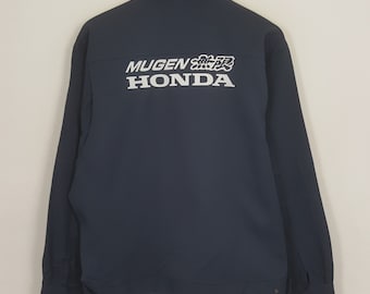 May include: Navy blue jacket with the white text "MUGEN 無限 HONDA" printed on the back. The jacket has a collared neckline, long sleeves, and button closures. The jacket is a solid color.