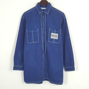 May include: A long-sleeved, cobalt blue shirt with white stitching details. Features two front pockets and a rectangular patch that reads "Durable Wash & Wear". The shirt is button-down with a collared neckline.