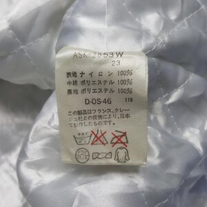 May include: Close-up of a white fabric tag with Japanese text and care symbols. The tag includes the text "ASK-2853 W" and "D-OS-46". The fabric appears to be quilted.