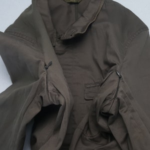 Puede incluir: Chaqueta verde oliva con cuello abotonado y un peque&ntilde;o bolsillo. La chaqueta tiene dos bolsillos con cremallera en las mangas. La marca "AAR" es visible en el cuello.
