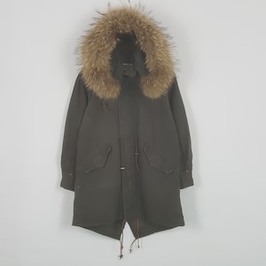 May include: An olive green parka with a fur-lined hood. The long coat features a drawstring waist, two front pockets, and a button-up closure. The fur trim is a light brown color.