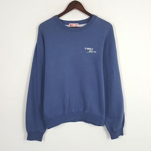 May include: A blue sweatshirt with the text "TRO Sports" in white and light blue. The sweatshirt has a crew neck and long sleeves. The brand logo "TRO" is on the upper back.