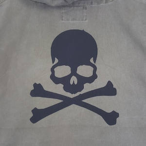 Puede incluir: Una sudadera con capucha gris con un dise&ntilde;o de calavera y huesos cruzados azul oscuro en la espalda. La calavera tiene cuencas oculares grandes y una nariz prominente. Los huesos cruzados est&aacute;n colocados debajo de la calavera, creando un dise&ntilde;o cl&aacute;sico de tem&aacute;tica pirata.