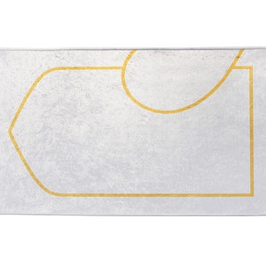 May include: A rectangular prayer rug with a white background and a gold geometric design. The rug has a textured surface and fringed edges. The gold design outlines a central rectangular shape and a curved top.