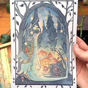 Könnte beinhalten: Eine fantasievolle Illustration eines hellblauen Drachen in einem Wald. Das Bild zeigt Pilze, einen Vogel und einen Sternenhimmel. Der Rahmen wird von einem dekorativen Rand umgeben, wobei der Drache im Mittelpunkt steht.