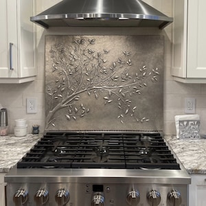 Panel de cocina moderno con diseño minimalista de ramas de olivo y revestimiento de cobre.