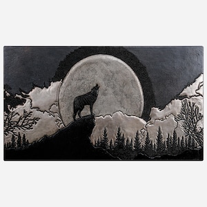 Puede incluir: Un arte de pared de cuero estampado en negro y plata que representa a un lobo aullando a la luna llena en un entorno de bosque.