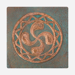 Può includere: Targa quadrata in metallo color rame con patina turchese. La targa presenta un disegno a spirale centrale all'interno di una cornice circolare, circondato da un motivo a stella. Il disegno è in rilievo, creando un effetto tridimensionale.