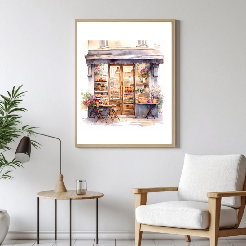 May include: Watercolor painting of a storefront with a brown door and windows displaying baked goods. There are two tables and chairs set up outside the shop.