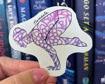May include: A white sticker with a purple and pink mandala design. The sticker features a silhouette of a person in a yoga pose with the word "Namaste" written above the figure.