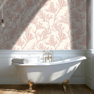 May include: A bathroom with a white clawfoot tub and coral-colored wallpaper. The wallpaper features a repeating pattern of coral branches on a cream background. The tub has gold-colored feet and fixtures, and a rolled-up white towel rests on the edge.