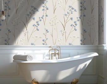 May include: A white clawfoot bathtub with gold accents and a rolled towel sits in front of a floral wallpaper. The wallpaper features a repeating pattern of blue and white flowers on a beige background. The bathroom has a classic, elegant design.