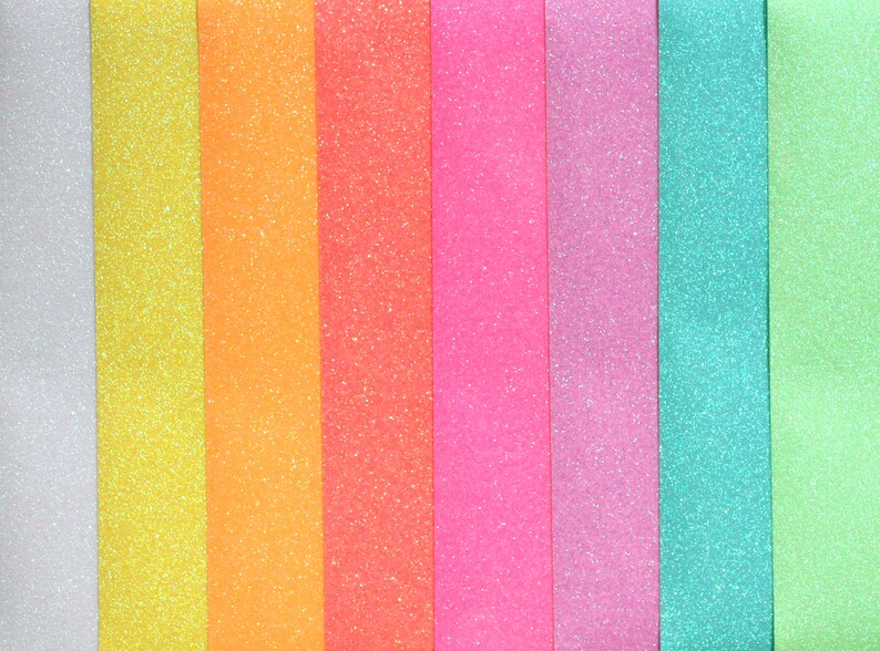 Puede incluir: Una colecci&oacute;n de nueve tiras de papel con brillantina en varios colores, incluyendo blanco, amarillo, naranja, rosa, morado, azul y verde.