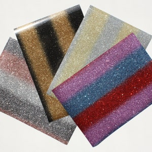 Könnte beinhalten: Vier Blätter Glitzerpapier in verschiedenen Farben und Mustern. Die Blätter sind in einem Stapel angeordnet, wobei das oberste Blatt ein gold-schwarz gestreiftes Muster hat. Die anderen Blätter sind ein silber-weiß gestreiftes Muster, ein pink-blau gestreiftes Muster und ein rot-lila gestreiftes Muster.