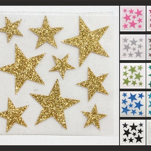Könnte beinhalten: Eine Blatt mit goldenen Glitzer-Stern-Aufklebern. Das Blatt ist in 12 Abschnitte unterteilt, jeder mit einer anderen Farbe von Glitzer-Stern-Aufklebern. Die Farben umfassen Pink, Rot, Silber, Braun, Grün, Türkis, Blau, Schwarz und Weiß.