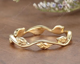 May include: A delicate gold band ring with a leaf design. The ring is made of a thin band of gold with small leaves that are connected by a thin vine. The ring is handmade and has a simple, elegant design.
