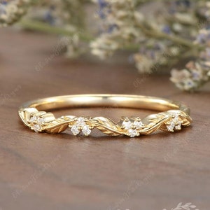 May include: A delicate gold band with a twisted design and small diamonds set in the band. The band is handmade and features a floral motif.