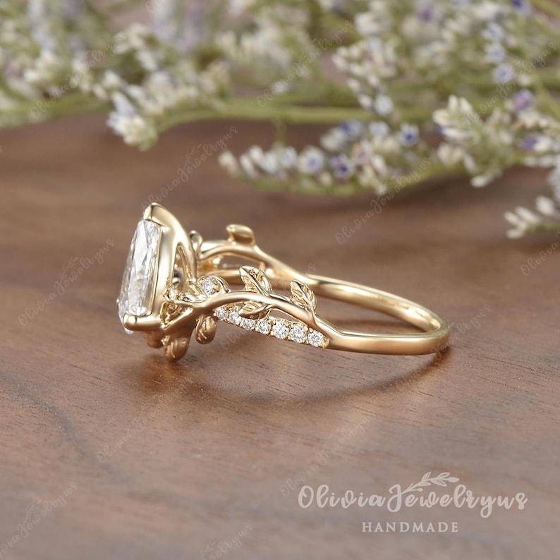 May include: A gold ring with a pear-shaped diamond set in a delicate floral design. The ring features a band with a vine-like pattern and small diamonds.
