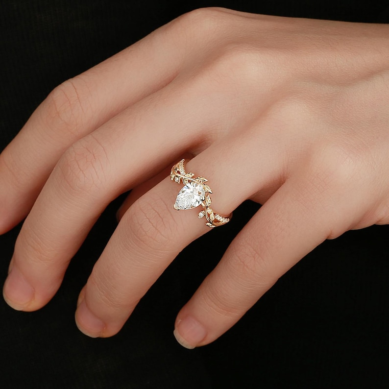 May include: A gold ring with a pear-shaped diamond set in a delicate leaf design.