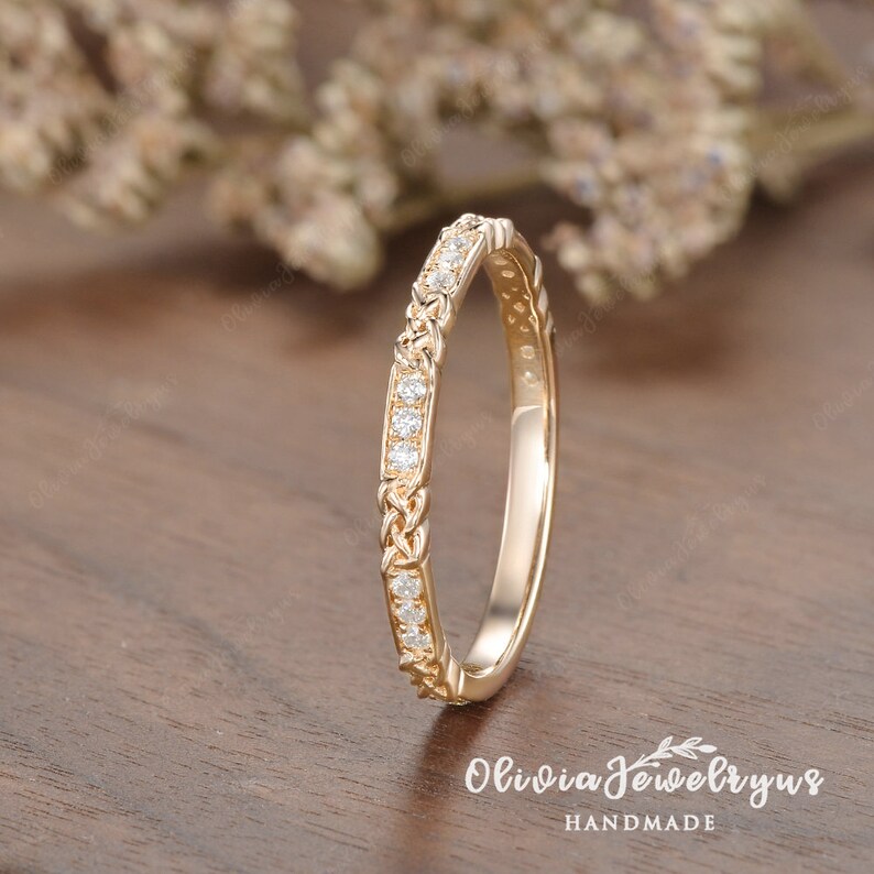 May include: A delicate gold band with a braided design and a row of small diamonds.
