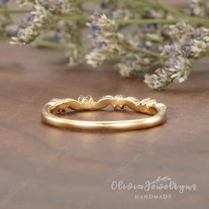 May include: A delicate gold band with a floral design and small gemstones. The band is thin and has a subtle curve. The ring is handmade.