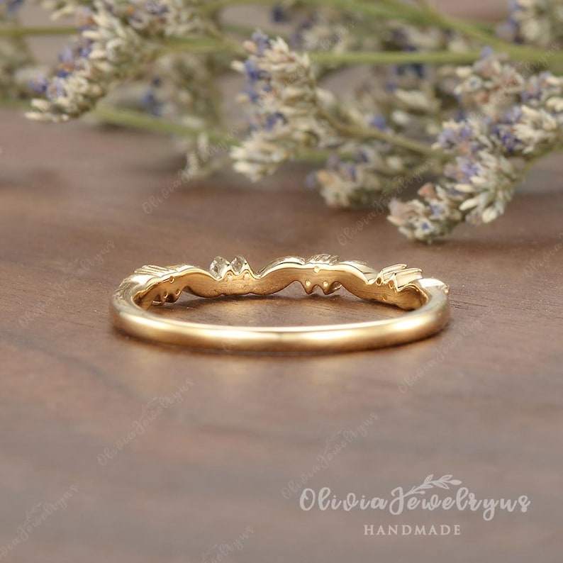 May include: A delicate gold band with a floral design and small gemstones. The band is thin and has a subtle curve. The ring is handmade.