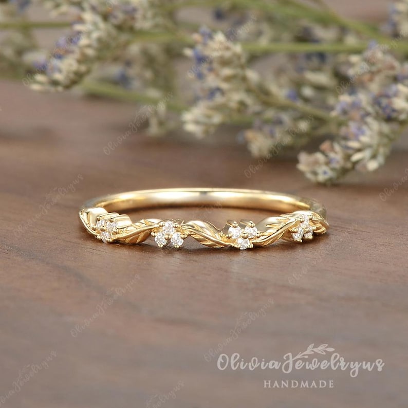 May include: A delicate gold band with a twisted design and small diamonds set in the band. The band is handmade and features a floral motif.