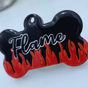 May include: Black bone-shaped dog tag with red and orange flames and the word "Flame" in white lettering.