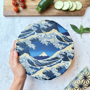 Può includere: Un involucro per alimenti riutilizzabile blu e bianco con un design a onde giapponesi. L'involucro presenta una montagna e onde sullo sfondo.