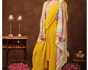 Può includere: Una gonna drappeggiata gialla con una sciarpa a righe colorate e un top giallo ricamato. La modella indossa orecchini dorati e scarpe dorate.