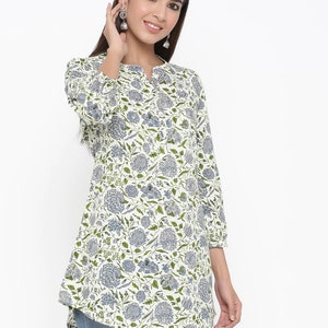 May include: A white cotton tunic top with a blue and green floral print. The top has a V-neck and three-quarter sleeves.