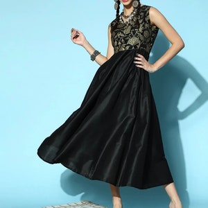 May include: A black sleeveless dress with a gold floral print bodice and a flowing skirt. The dress is worn by a model with long dark hair and gold earrings.