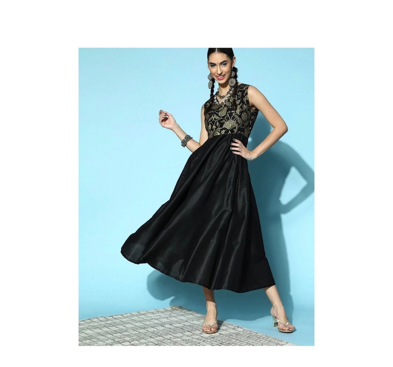 May include: A black sleeveless dress with a gold embroidered bodice and a flowing skirt. The dress is worn by a model with long dark hair and gold earrings.