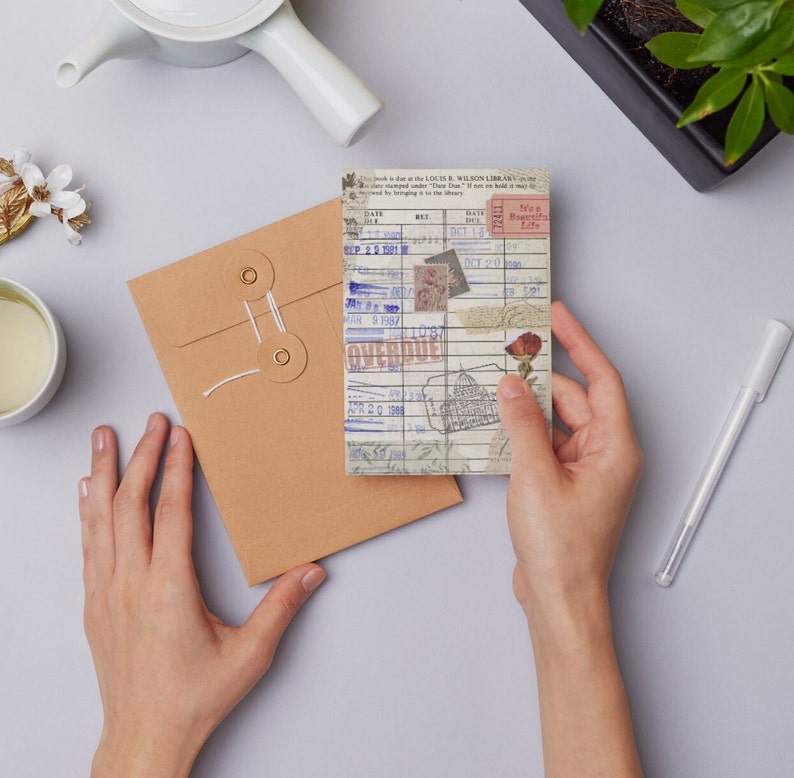 May include: A vintage library card with a blue and white design. The card has a red flower sticker and a sticker that says "Non-Beautiful Life". The card has dates and numbers written on it, including "SEP 2 2 1981", "OCT 18", "DEC 20", "MAR 9 1997", "APR 2 0 1988", and "OVERDUE".