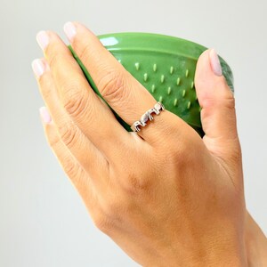 Könnte beinhalten: Ein silberner Ring mit einem Design aus fünf Elefanten, die in einer Reihe stehen.