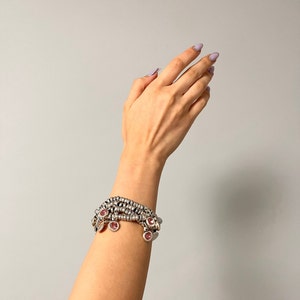 Könnte beinhalten: Ein silbernes Armband mit mehreren Strängen und rosa Edelstein-Anhängern.