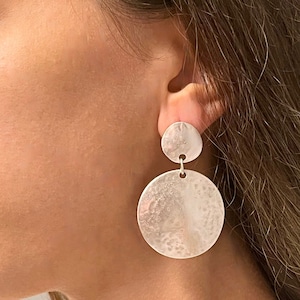 May include: Silver dangle earrings with two round hammered discs. The larger disc is approximately 5 cm in diameter.