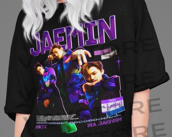 Puede incluir: Camiseta negra con un estampado gráfico de una banda de K-pop, con el nombre "JAEMIN" en texto morado y las palabras "NCT NA JAEHYUN" en texto blanco. Los miembros de la banda visten ropa colorida y tienen una pose dinámica.