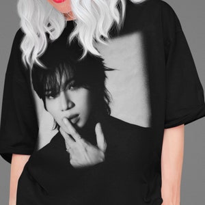 Puede incluir: Camiseta gráfica en blanco y negro con un retrato de una persona con el pelo corto y oscuro. La persona mira a la cámara y tiene el dedo en los labios.