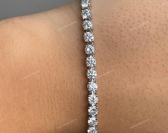 May include: A silver tennis bracelet with a row of round, clear cubic zirconia stones.